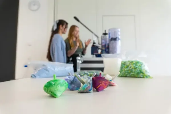 Bunte, farbverlaufene Kunststoff-Kreisel auf einem Tisch im SKZ-Labor – Endprodukte eines Experiments, bei dem recycelte Kunststoffe zerkleinert und neu geformt werden. Teil des Projekts „Plastik verstehen – Zukunft gestalten“.