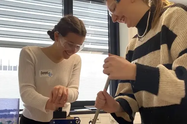 Zwei Schülerinnen mit Schutzbrillen bedienen einen kleinen Hand-Schredder, um Kunststoffproben zu zerkleinern – Teil des SKZ-Projekts „Plastik verstehen – Zukunft gestalten“. Sie lernen dabei spielerisch, wie Recycling funktioniert und warum ein nachhaltiger Umgang mit Kunststoffen so wichtig ist.