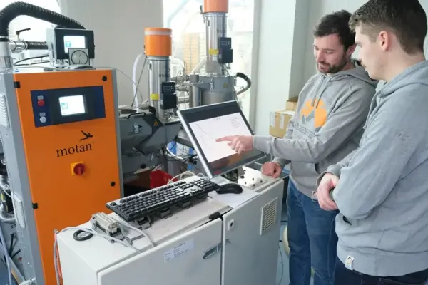 Studierende beobachten die Fertigung eines Bauteils an einer Maschine.