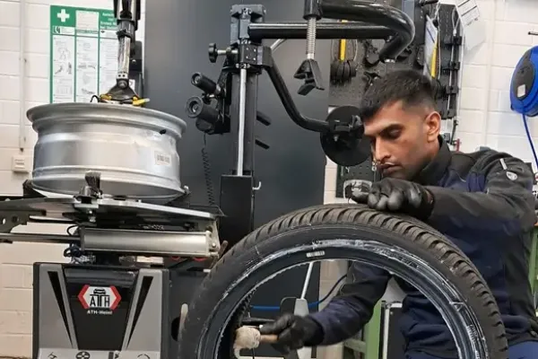 Ein Auszubildender bereitet einen Reifen mit einem Werkzeug vor.