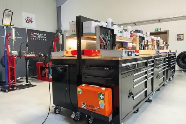 Eine gut ausgestattete Werkstatt mit mehreren Werkzeugwagen und einem Erste-Hilfe-Koffer.