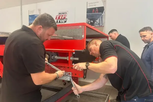 Drei Teilnehmer einer Schulung arbeiten gemeinsam an einer roten Maschine.