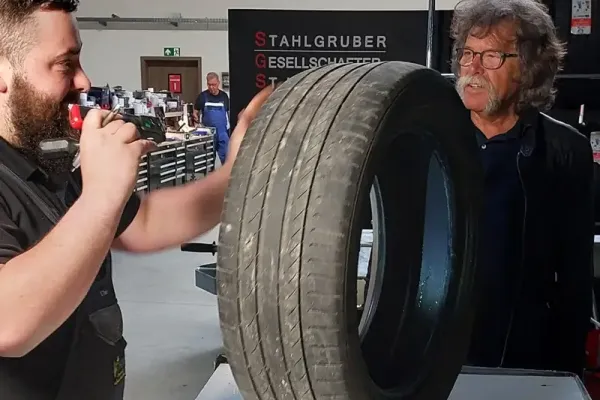 Zwei Teilnehmer einer Schulung prüfen einen Reifen an einem Tisch.