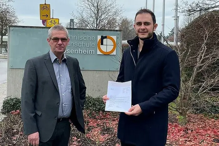 Ein Studierender erhält von einem Professor der Technischen Hochschule Rosenheim die Urkunde für ein Stipendium der STAHLGRUBER GESELLSCHAFTER-STIFTUNG.