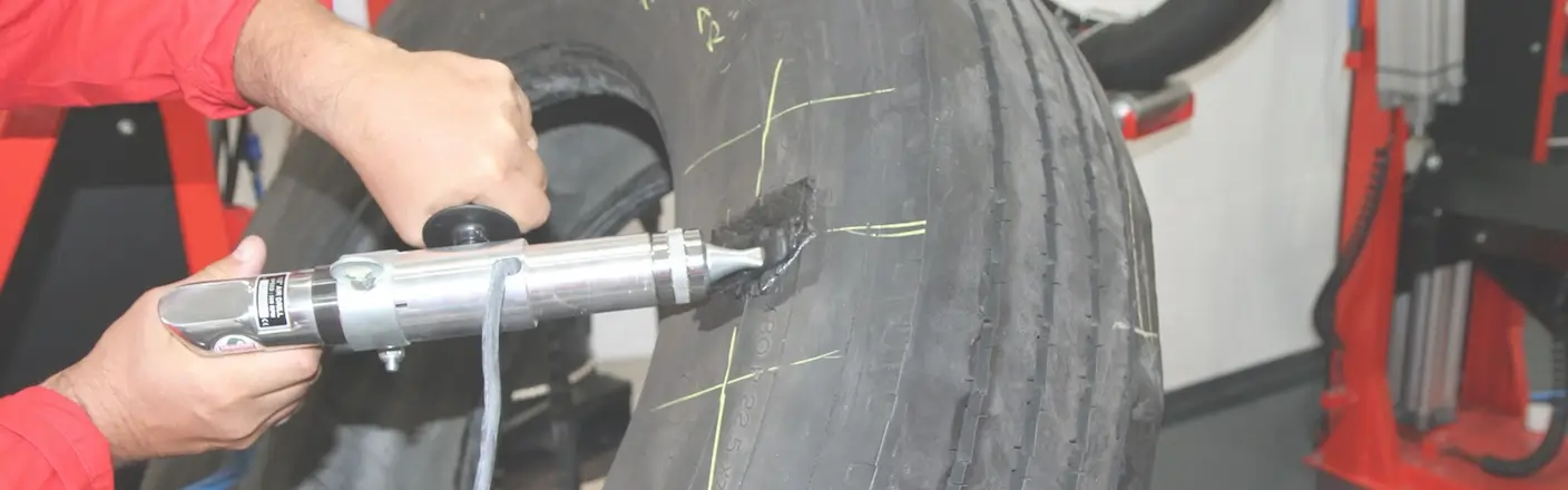 Ein Vulkaniseur repariert einen Reifen mit einem Spezialwerkzeug – Symbol für die Förderung der handwerklichen Ausbildung durch die STAHLGRUBER GESELLSCHAFTER-STIFTUNG.